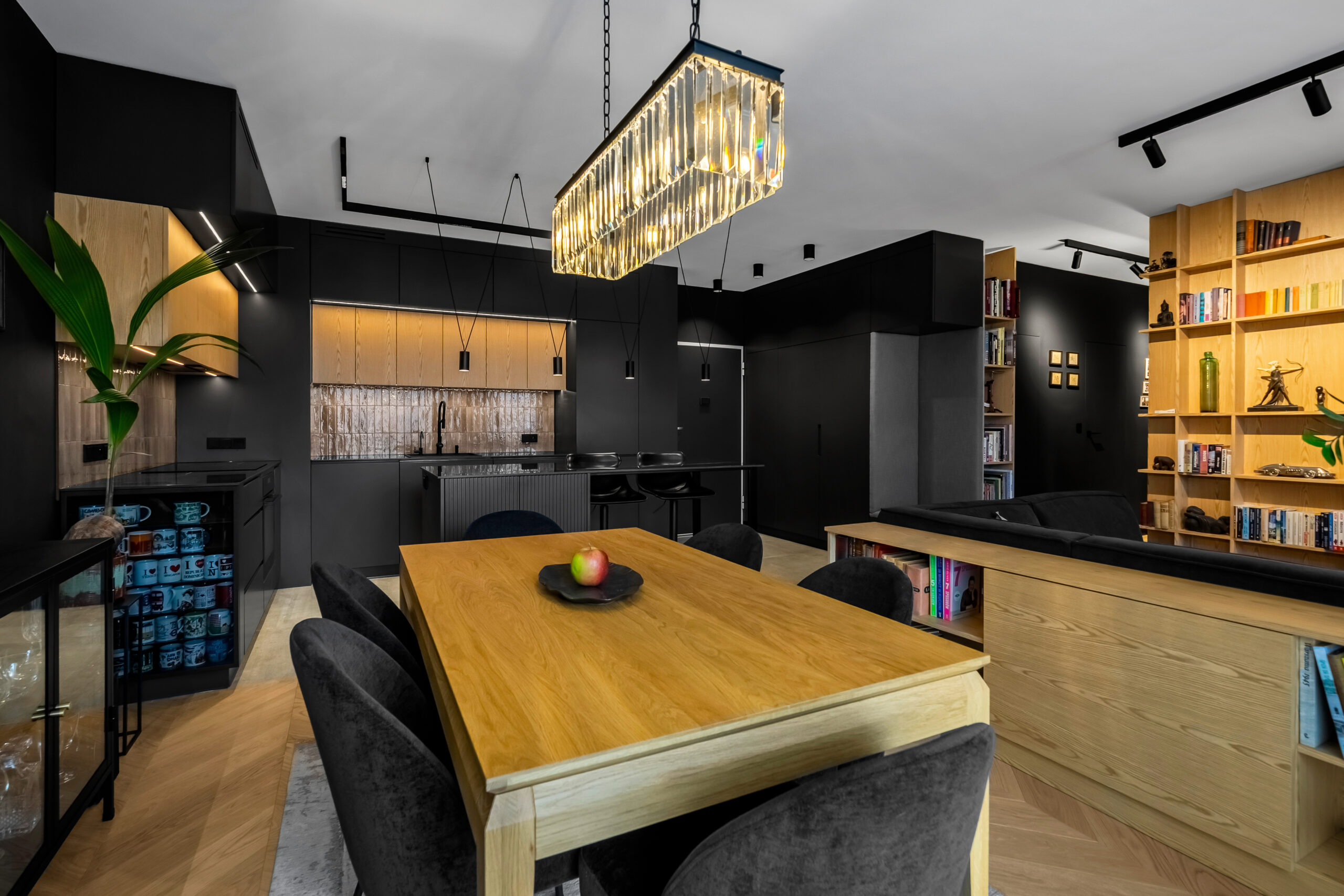 Kuchnia czarna i jadalnia z drewnianym stołem