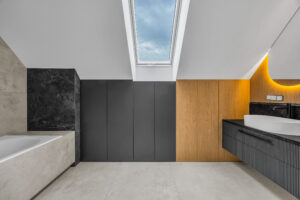 Czarna szafka łazienkowa pod skosami z elementami drewnianej zabudowy wykonana na wymiar.