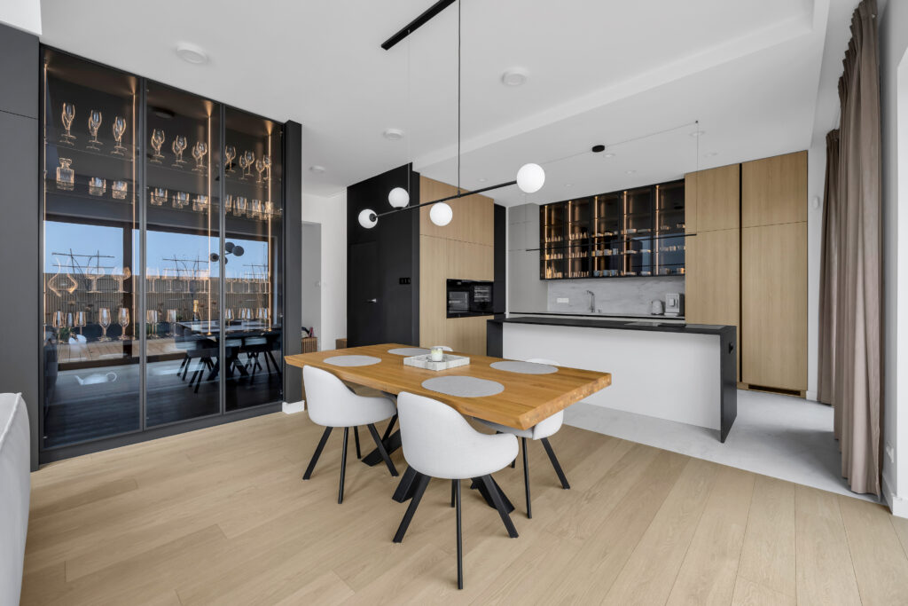 Szeroki widok kuchni połączonej z jadalnią i wyspą.