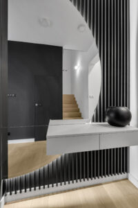 Przedpokój z lamelami, lustrem i wiszącą szafką.