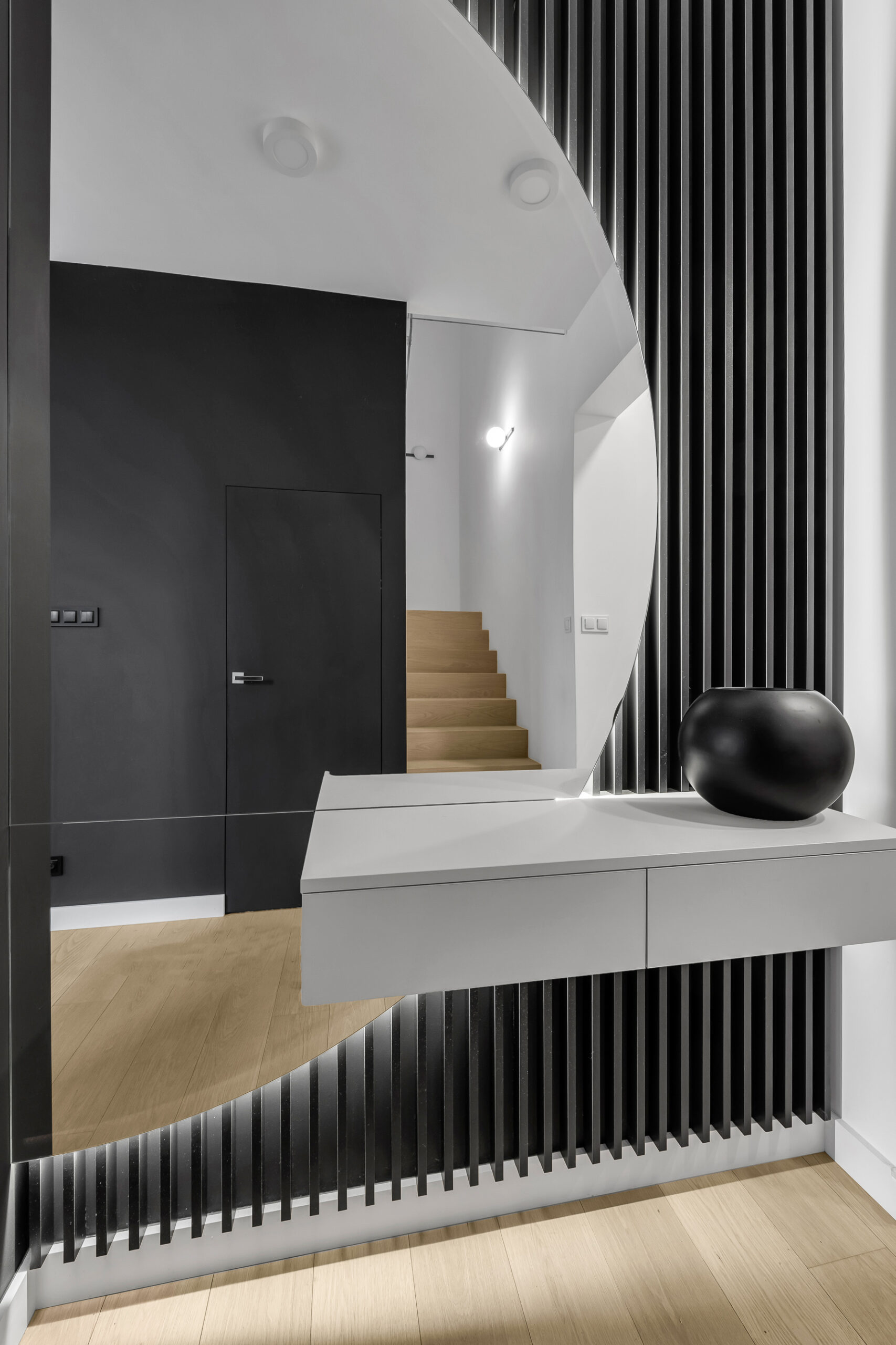 Przedpokój z lamelami, lustrem i wiszącą szafką.