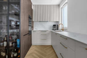 Zabudowa kuchenna na wymiar z ryflowanymi frontami wiszącymi i elementami z naturalnego drewna.