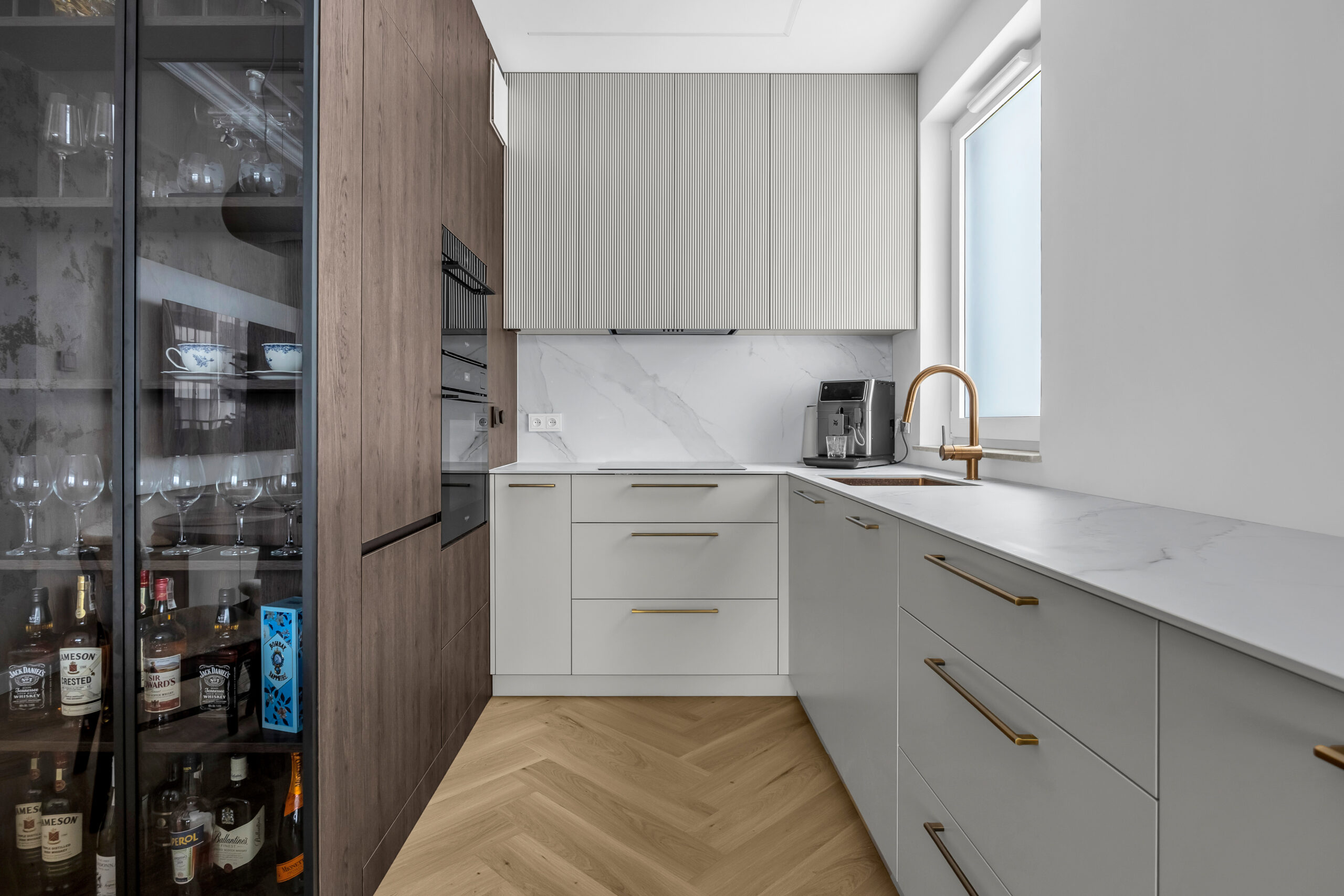 Zabudowa kuchenna na wymiar z ryflowanymi frontami wiszącymi i elementami z naturalnego drewna.