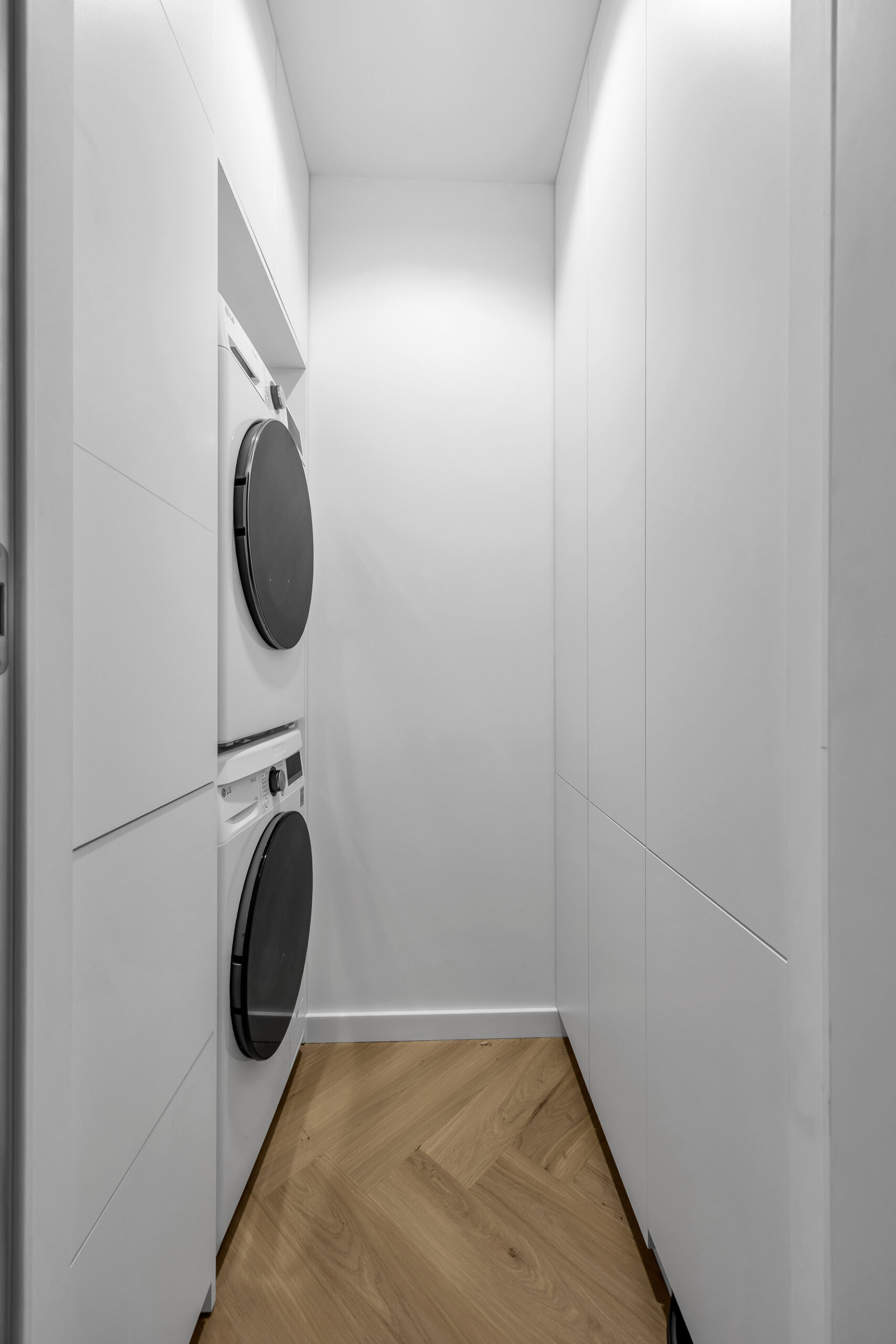 Zabudowa pralni na wymiar wykonana z białej płyty meblowej.