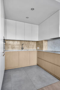 Zabudowa kuchenna z białymi frontami górnymi i drewnianymi szafkami dolnymi.