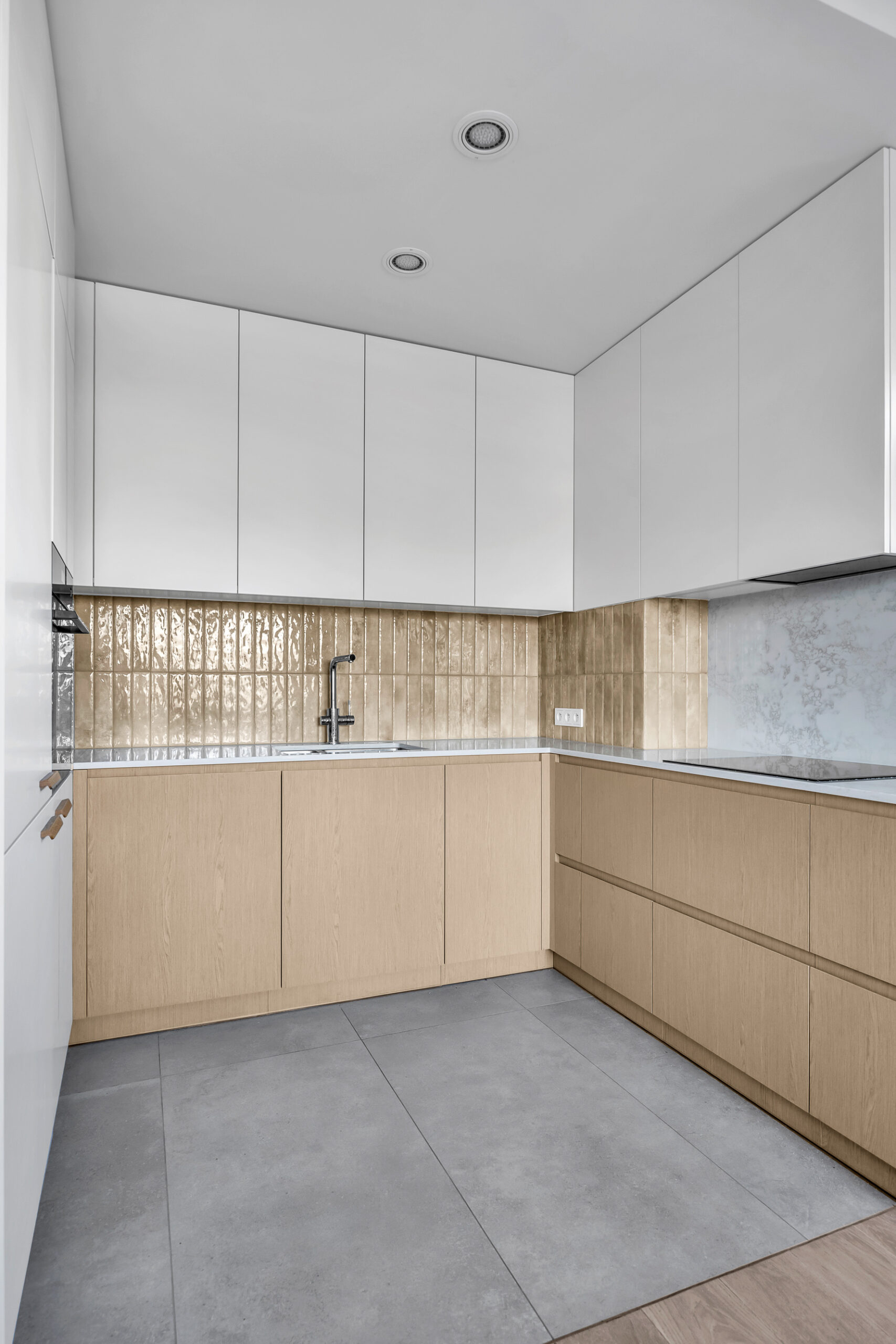 Zabudowa kuchenna z białymi frontami górnymi i drewnianymi szafkami dolnymi.